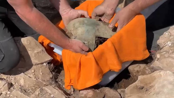 A estrutura de pedra onde estava o capacete foi encontrada separada de todas as sepulturas no monte funerário, e sugere que ela foi projetada como um local para oferenda votiva “a antepassados falecidos ou parte de alguma prática de culto relacionada a todo o monte e não um indivíduo em particular ou uma sepultura”. (Foto: YouTube)